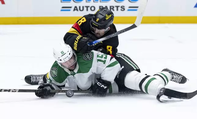 Vancouver Canucks' Conor Garland (8) and Dallas Stars' Colin Blackwell (15) fall as they vie for the puck during the second period of an NHL hockey game in Vancouver, British Columbia, Sunday, March 9, 2025. (Ethan Cairns/The Canadian Press via AP)