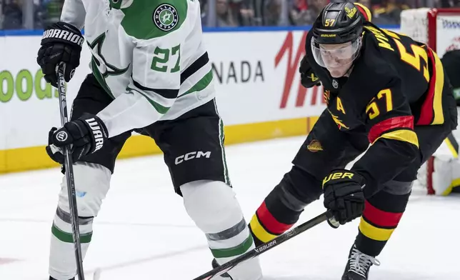 Dallas Stars' Mason Marchment (27) and Vancouver Canucks' Tyler Myers (57) vie for the puck during the second period of an NHL hockey game in Vancouver, British Columbia, Sunday, March 9, 2025. (Ethan Cairns/The Canadian Press via AP)