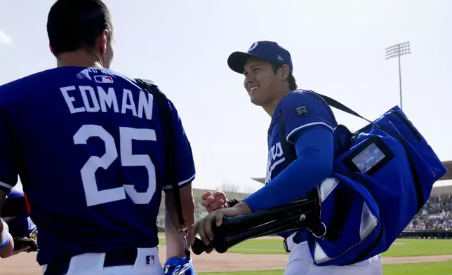 Los Angeles Dodgers' Shohei Ohtani, right, of Japan, smiles as he leaves the game with Dodgers' Tommy Edman (25) during the sixth inning of a spring training baseball game against the Texas Rangers Thursday, March 6, 2025, in Phoenix. (AP Photo/Ross D. Franklin)