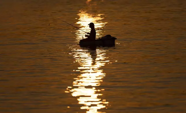 Ernesto Abel Casillas fishes on a makeshift raft at dawn in Cojimar, east of Havana, Tuesday, March 25, 2025. (AP Photo/Ramon Espinosa)