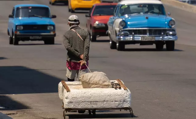 A fisherman transports his makeshift raft through traffic along the boardwalk in Havana, Monday, March 24, 2025. (AP Photo/Ramon Espinosa)