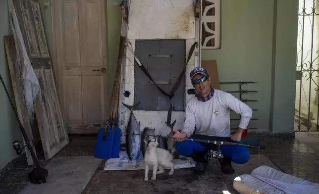 Fisherman Miguel Gonzalez poses with the day's catch and his makeshift raft at his home in Cojimar, east of Havana, Tuesday, March 25, 2025. (AP Photo/Ramon Espinosa)