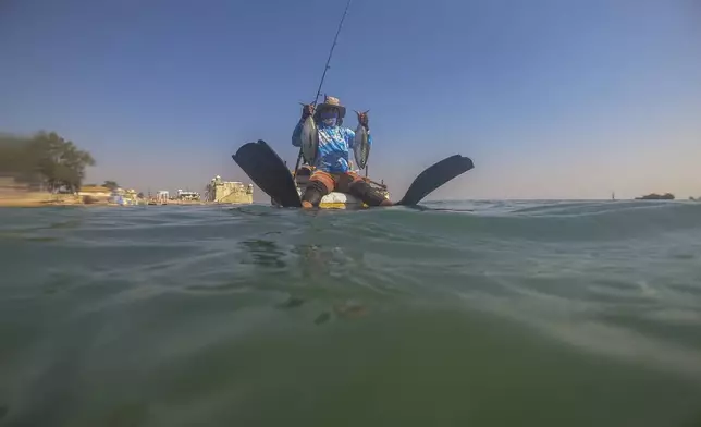 A fisherman sits on his makeshift "corcho" raft as he shows off his day's catch in Cojímar, east of Havana, Cuba, Thursday, March 20, 2025. (AP Photo/Ramon Espinosa)