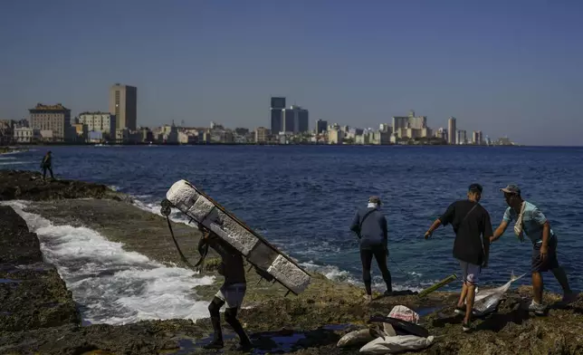 A fisherman carries a makeshift raft on his back in Havana, Wednesday, March 19, 2025. (AP Photo/Ramon Espinosa)