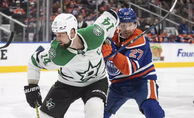 Dallas Stars' Jamie Benn (14) and Edmonton Oilers' Brett Kulak (27) battle for the puck during the third period of an NHL game in Edmonton on Wednesday, March 26, 2025. (Jason Franson/The Canadian Press via AP)