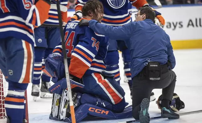 Edmonton Oilers goalie Stuart Skinner (74) is checked on by medical staff against the Dallas Stars during third period NHL action in Edmonton, Alberta, Wednesday, March 26, 2025. (Jason Franson/The Canadian Press via AP)