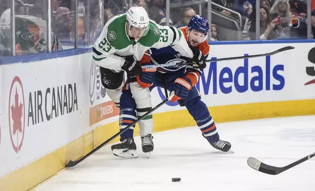 Dallas Stars' Esa Lindell (23) and Edmonton Oilers' Zach Hyman (18) battle for the puck during the second period of an NHL game in Edmonton on Wednesday, March 26, 2025. (Jason Franson/The Canadian Press via AP)