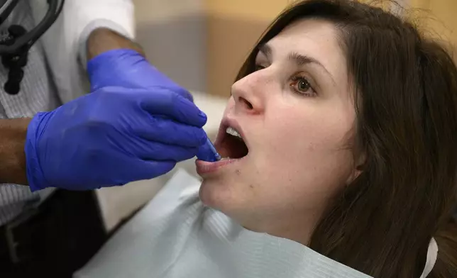 Alexander Daniel, DDS, left, demonstrates fluoride treatment on resident Cameron Onken, right, at the Johns Hopkins Outpatient Center, Friday, Feb. 28, 2025, in Baltimore. (AP Photo/Nick Wass)