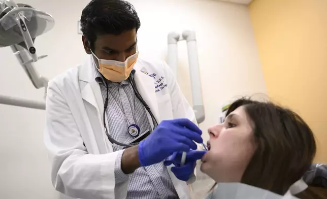 Alexander Daniel, DDS, left, demonstrates fluoride treatment on resident Cameron Onken, right, at the Johns Hopkins Outpatient Center, Friday, Feb. 28, 2025, in Baltimore. (AP Photo/Nick Wass)
