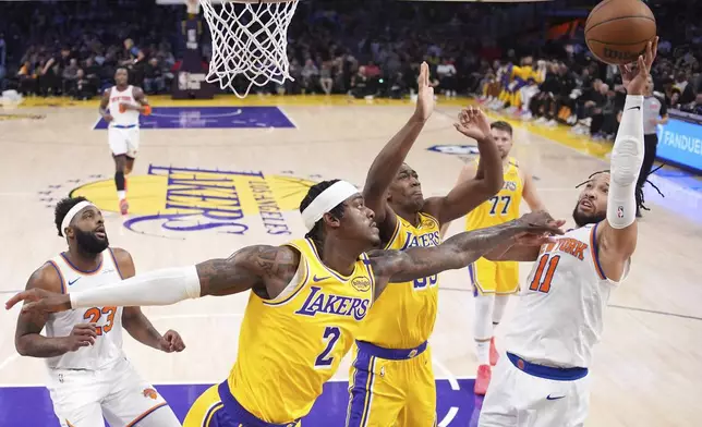 New York Knicks guard Jalen Brunson (11) shoots as Los Angeles Lakers forward Jarred Vanderbilt (2) and center Trey Jemison III (55) defend during the first half of an NBA basketball game Thursday, March 6, 2025, in Los Angeles. (AP Photo/Mark J. Terrill)