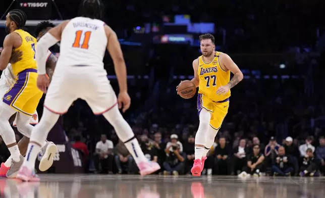Los Angeles Lakers guard Luka Doncic, right, dribbles as New York Knicks guard Jalen Brunson waits for him during the first half of an NBA basketball game Thursday, March 6, 2025, in Los Angeles. (AP Photo/Mark J. Terrill)