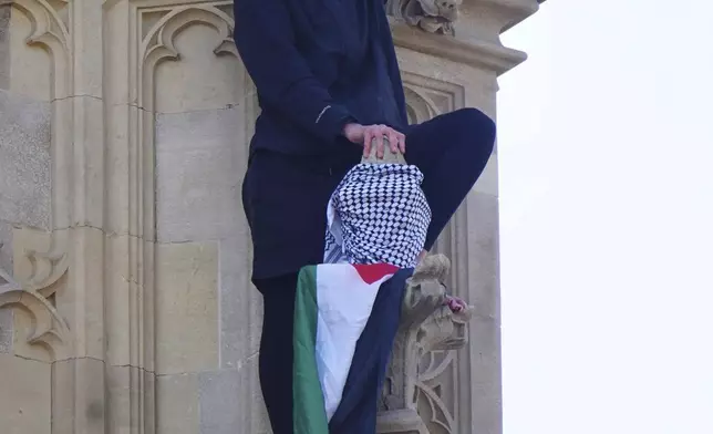 A man with a Palestine flag after he climbed up Elizabeth Tower, which houses Big Ben at the Palace of Westminster in London. Saturday, March 8, 2025. (James Manning/PA via AP)