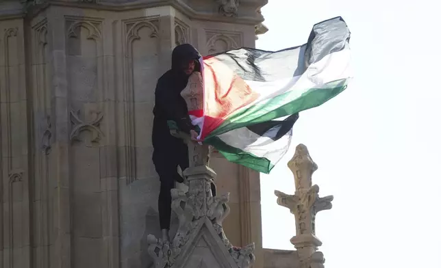A man holds a Palestinian flag after he climbed up Elizabeth Tower, which houses Big Ben at the Palace of Westminster in London, Saturday, March 8, 2025. (Jeff Moore/PA via AP)