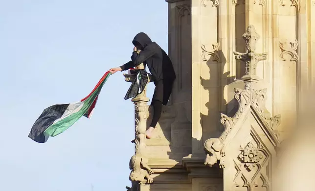 A man holds a Palestinian flag after he climbed up Elizabeth Tower, which houses Big Ben at the Palace of Westminster in London, Saturday, March 8, 2025. (Jeff Moore/PA via AP)