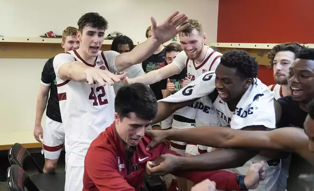 Stanford forward Maxime Raynaud (42) and celebrates with teammates and Alex Yano, director of basketball operations, inside the locker room after the team's victory over California in an NCAA college basketball game Saturday, Feb. 22, 2025, in Stanford, Calif. (AP Photo/Godofredo A. Vásquez)