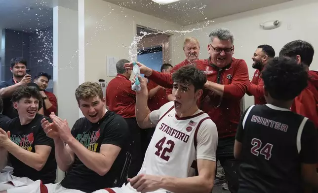 Stanford forward Maxime Raynaud (42) douses head coach Kyle Smith, wearing glasses, with water in the locker room after the team's victory over California in an NCAA college basketball game Saturday, Feb. 22, 2025, in Stanford, Calif. (AP Photo/Godofredo A. Vásquez)