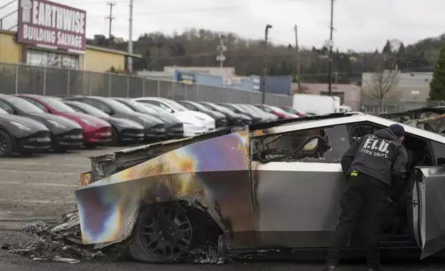 A member of the Seattle Fire Department inspects a burned Tesla Cybertruck at a Tesla lot in Seattle, Monday, March 10, 2025. (AP Photo/Lindsey Wasson)