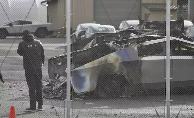 A person inspects a burned Cybertruck in a Tesla lot in Seattle, Monday, March 10, 2025. (AP Photo/Manuel Valdes)