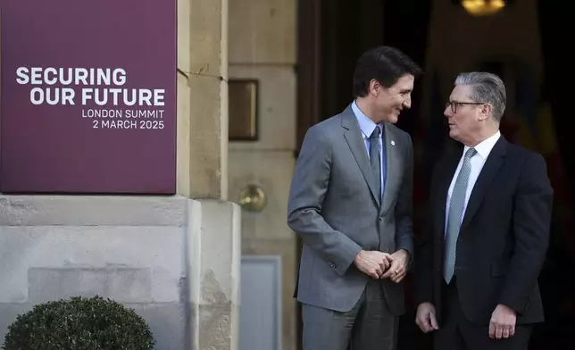 Britain's Prime Minister Keir Starmer, right, welcomes Canadian Prime Minister Justin Trudeau to the European leaders' summit to discuss Ukraine, at Lancaster House, London, Sunday March 2, 2025. (Toby Melville/Pool via AP)