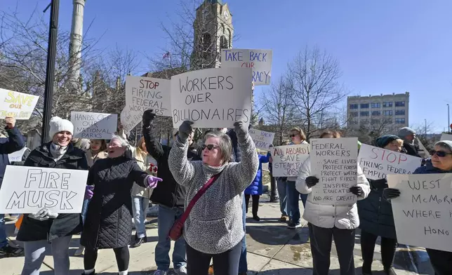 Protesters carry signs under the Columbus Statue at the Scranton Court House Square at a "Save Steamtown" rally to protest the Trump administration layoffs at the Steamtown National Historic Site in Scranton, Pa., Saturday, Feb. 22, 2025. (Aimee Dilger/WVIA via AP)