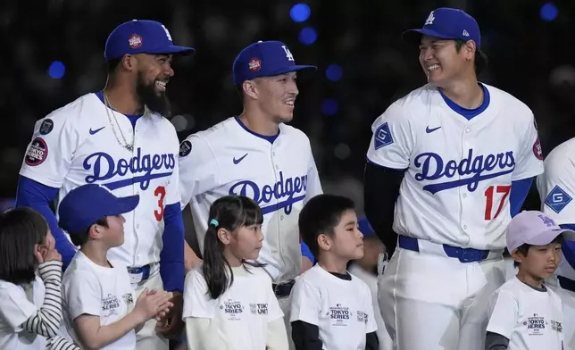 Los Angeles Dodgers' Teoscar Hernandez, left, Tommy Edman, center, and Shohei Ohtani (17) talk as they stand on the field during team introductions before an MLB Tokyo Series baseball game against the Chicago Cubs in Tokyo, Japan, Wednesday, March 19, 2025. (AP Photo/Eugene Hoshiko)