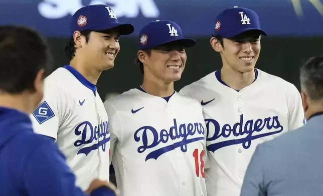 Los Angeles Dodgers' Shohei Ohtani, left, Yoshinobu Yamamoto, center, and Roki Sasaki, right, pose for a photo after the team's win in an MLB Tokyo Series baseball game against the Chicago Cubs in Tokyo, Japan, Wednesday, March 19, 2025. (AP Photo/Eugene Hoshiko)