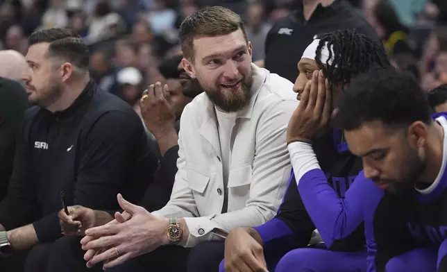 Injured Sacramento Kings forward Domantas Sabonis, center, looks on from the bench in the first half of an NBA basketball game against the Denver Nuggets Wednesday, March 5, 2025, in Denver. (AP Photo/David Zalubowski)