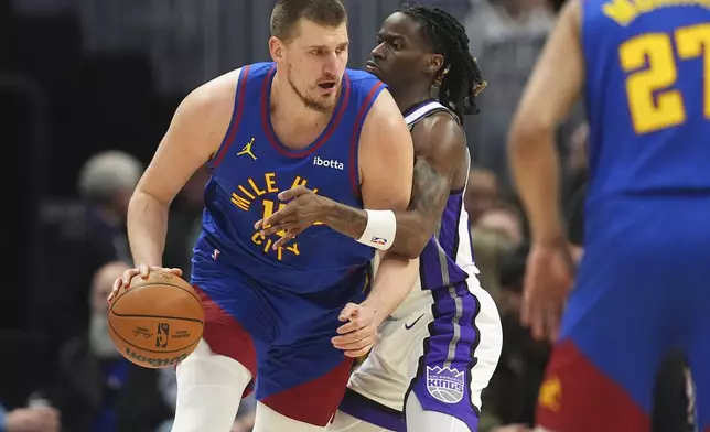Denver Nuggets center Nikola Jokic, left, drives to the net as Sacramento Kings guard Keon Ellis defends in the first half of an NBA basketball gme Wednesday, March 5, 2025, in Denver. (AP Photo/David Zalubowski)