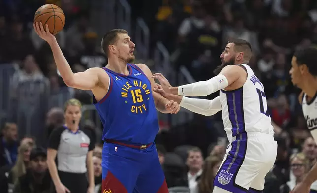 Denver Nuggets center Nikola Jokic, left, looks to pass the ball as Sacramento Kings center Jonas Valanciunas defends in the first half of an NBA basketball game Wednesday, March 5, 2025, in Denver. (AP Photo/David Zalubowski)