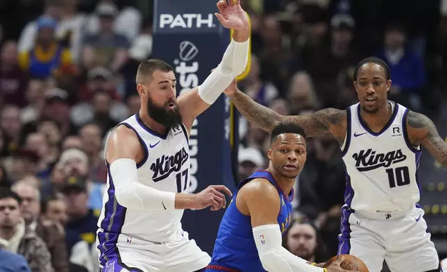 Denver Nuggets guard Russell Westbrook, center, looks to pass the ball as Sacramento Kings center Jonas Valanciunas, left, and forward DeMar DeRozan defend in the first half of an NBA basketball game Wednesday, March 5, 2025, in Denver. (AP Photo/David Zalubowski)