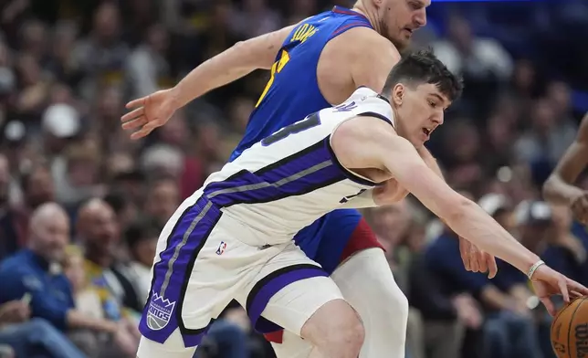 Sacramento Kings forward Jake LaRavia, front, pursues a loose ball with Denver Nuggets center Nikola Jokic in the first half of an NBA basketball game Wednesday, March 5, 2025, in Denver. (AP Photo/David Zalubowski)