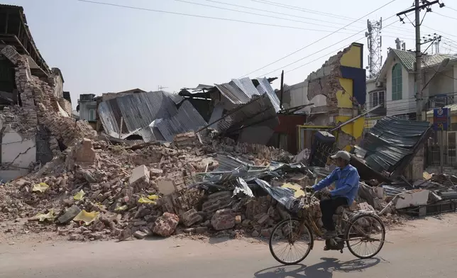 A local man rides a bicycle past a damaged building in the aftermath of an earthquake, in Naypyitaw, Myanmar, Sunday, March 30, 2025. (AP Photo/Aung Shine Oo)