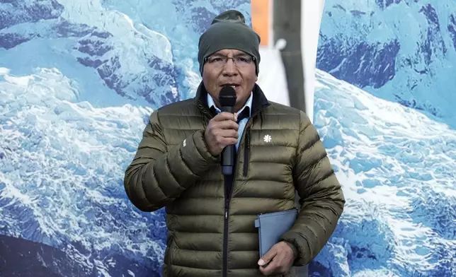 Peruvian farmer Luciano Lliuya speaks to the media in front of glacier pictures held by activists at the Higher Regional Court in Hamm, Germany, before a first hearing of his climate damages case against the German energy company RWE for its carbon emissions, which may have been contributing to the melting of a nearby glacier that could flood his home, Monday, March 17, 2025. (AP Photo/Martin Meissner)
