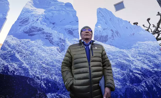 The plaintiff Peruvian farmer Luciano Lliuya stands in front of glacier pictures held by activists at the Higher Regional Court in Hamm, Germany, for a first hearing of his climate damages case against the German energy company RWE for its carbon emissions, which may have been contributing to the melting of a nearby glacier that could flood his home, Monday, March 17, 2025. (AP Photo/Martin Meissner)