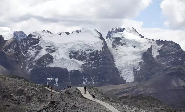 FILE - Tourists walk in front of the Tuco glacier in Huascaran National Park during a tour called the "Route of climate change" in Huaraz, Peru, Aug. 12, 2016. (AP Photo/Martin Mejia, File)