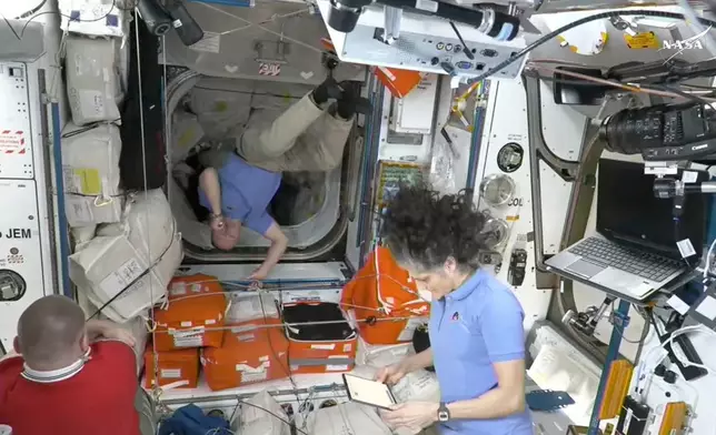 This image made from video by NASA shows Russian astronaut Alexei Ovchinin, left, Butch Wilmore, center, and Suni Williams wait to greet newly arrived astronauts after the SpaceX capsule docked with the International Space Station, Sunday, March 16, 2025. (NASA via AP)