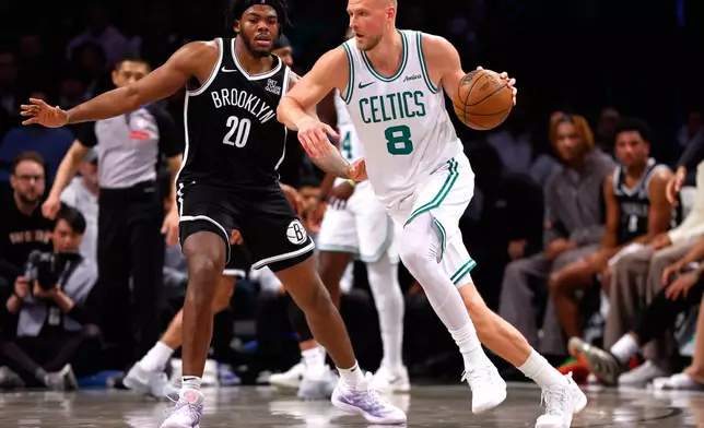 Boston Celtics center Kristaps Porzingis (8) drives to the basket against Brooklyn Nets center Day'Ron Sharpe (20) during the second half of an NBA basketball game, Saturday, March 15, 2025, in New York. (AP Photo/Noah K. Murray)