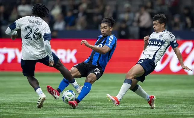Vancouver Whitecaps' Jean-Claude Ngando (26) and CF Montreal's Nathan-Dylan Saliba (19) vie for the ball as Whitecaps' Andres Cubas, right, watches during the second half of an MLS soccer match in Vancouver, British Columbia, Saturday, March 8, 2025. (Ethan Cairns/The Canadian Press via AP)