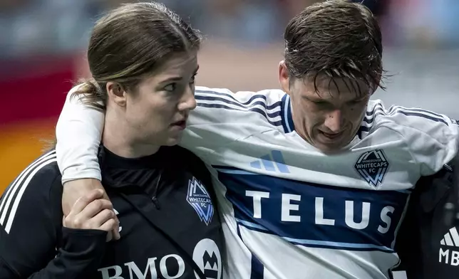 Vancouver Whitecaps' Ryan Gauld, right, leaves after an injury during the first half of an MLS soccer match against CF Montreal in Vancouver, British Columbia, Saturday, March 8, 2025. (Ethan Cairns/The Canadian Press via AP)