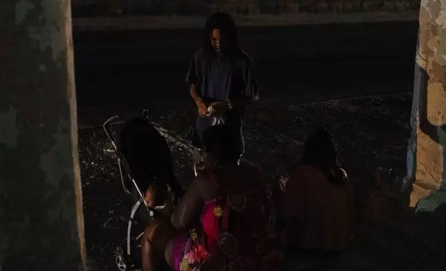 Residents wait outside on a street during a general blackout in Havana, Cuba, Friday, March 14, 2025. (AP Photo/Ramon Espinosa)