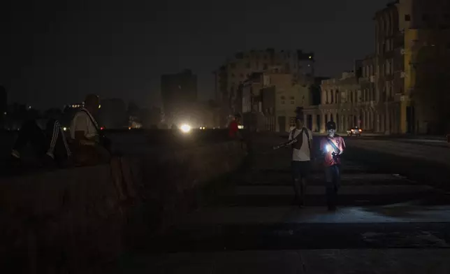 Residents walk on a street during a general blackout in Havana, Cuba, Friday, March 14, 2025. (AP Photo/Ramon Espinosa)