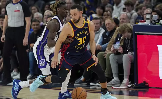 Golden State Warriors guard Stephen Curry (30) moves the ball while defended by Sacramento Kings guard Keon Ellis during the first half of an NBA basketball game Thursday, March 13, 2025, in San Francisco. (AP Photo/Godofredo A. Vásquez)