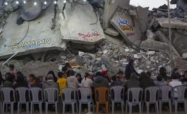 Palestinians sit at a large table surrounded by the rubble of destroyed homes and buildings as they gather for iftar, the fast-breaking meal, on the first day of Ramadan in Rafah, southern Gaza Strip, Saturday, March 1, 2025 (AP Photo/Abdel Kareem Hana)