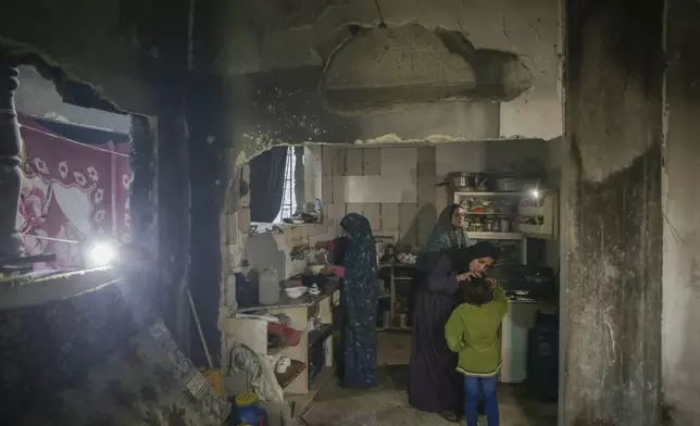 Fatima Al-Absi, center left, prepares food for her family's iftar, the fast-breaking meal, on the first day of Ramadan in their damaged apartment in Jabaliya, northern Gaza Strip, on Saturday, March 1, 2025. (AP Photo/Jehad Alshrafi)