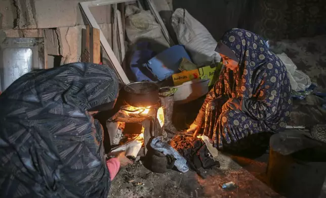 Fatima Al-Absi, left, and her daughter Nora prepare food for their family's iftar, the fast-breaking meal, on the first day of Ramadan in their damaged apartment in Jabaliya, northern Gaza Strip, on Saturday, March 1, 2025. (AP Photo/Jehad Alshrafi)