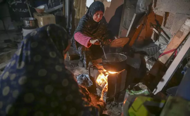 Fatima Al-Absi prepares food for her family's iftar, the fast-breaking meal, on the first day of Ramadan in their damaged apartment in Jabaliya, northern Gaza Strip, on Saturday, March 1, 2025. (AP Photo/Jehad Alshrafi)