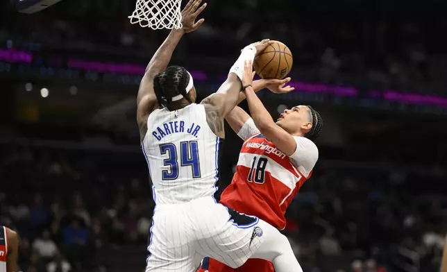 Washington Wizards forward Kyshawn George (18) is blocked by Orlando Magic center Wendell Carter Jr. (34) during the first half of an NBA basketball game, Friday, March 21, 2025, in Washington. (AP Photo/Nick Wass)