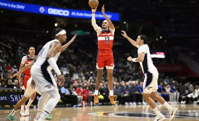 Washington Wizards guard Jordan Poole (13) shoots past Orlando Magic guard Anthony Black, right, during the first half of an NBA basketball game, Friday, March 21, 2025, in Washington. (AP Photo/Nick Wass)