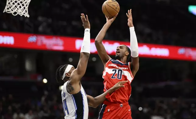 Washington Wizards forward Alex Sarr (20) shoots against Orlando Magic center Wendell Carter Jr., left, during the first half of an NBA basketball game, Friday, March 21, 2025, in Washington. (AP Photo/Nick Wass)