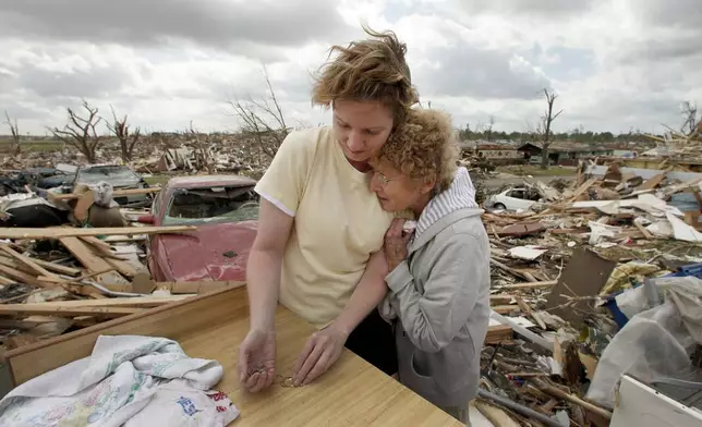 FILE- In this May 25, 2011 file photo, Beverly Winans hugs her daughter Debbie Surlin while salvaging items from Winans' devastated home in Joplin, Mo. (AP Photo/Charlie Riedel, file)